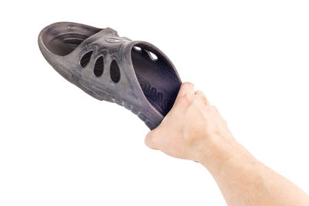 caucasian hand holding black rubber slipper like weapon against cockroach