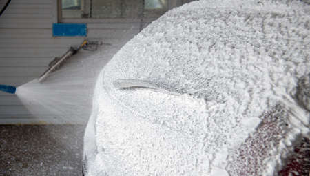A process of applying soap sud in indoor carwash station - closeup with selective focus.