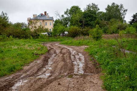 dirty clay mud road with puddles and tire tracks - closeup with selective focus and linear perspectiveの写真素材