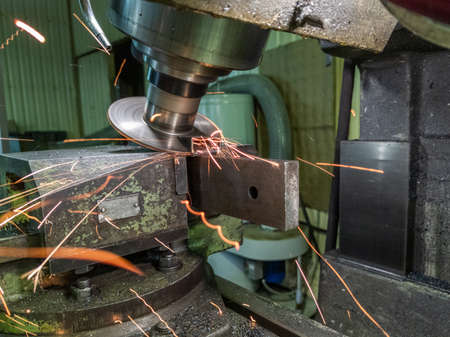 sloped disk industrial milling process with sparks - close-up with selective focus and blur
