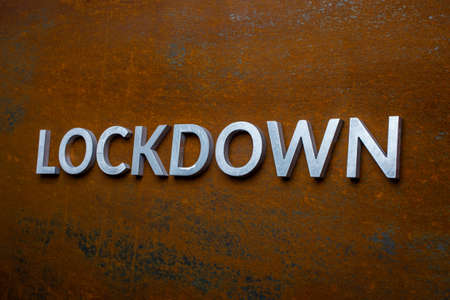 the word lockdown laid with silver metal letters on flat rusted steel sheet background in slanted linear perspectiveの写真素材