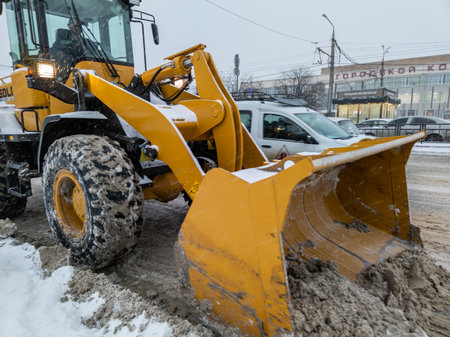 TULA, RUSSIA - NOVEMBER 21, 2020: Tractor with large scoop cleaning snow on road at winter day light.のeditorial素材