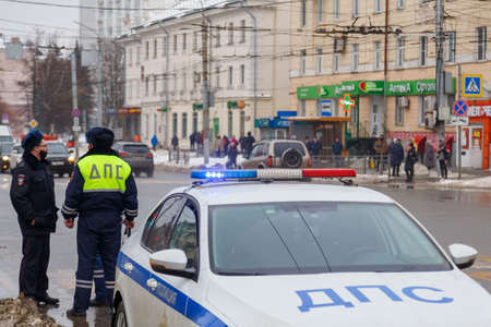 TULA, RUSSIA - JANUARY 23, 2021: Russian road police officers standing near patrol car on winter road - close-up with selective focus on roof lamp.のeditorial素材