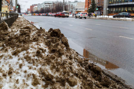 pile of dirty snow on side of winter city street, close-up with selective focus