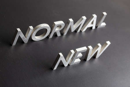 new normal word composed of silver metal letters on a flat matt black surface with diagonal perspectiveの写真素材