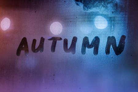 the word autumn handwritten on night wet window glass surfaceの写真素材