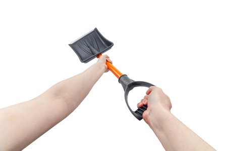 two white hands holding small black plastic snow shovel, isolatedの写真素材