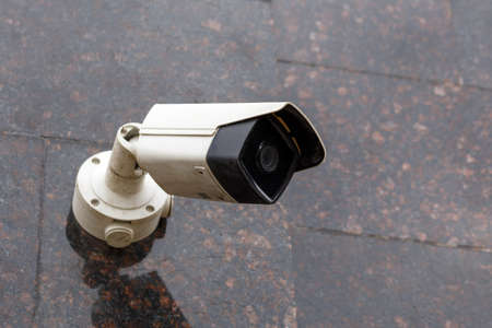 small cheap surveillance camera on tan brown granite wallの写真素材