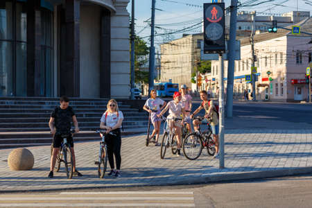 Tula, Russia - June 13, 2021: Group of young pedestrians with bicycles on the sidewalk waiting for a traffic light at sunny dayのeditorial素材