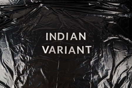 words indian variant laid with silver metal letters on crumpled black plastic bag backgroundの写真素材