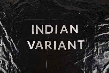 words indian variant laid with silver metal letters on crumpled black plastic bag background.の写真素材