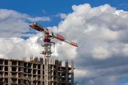 building process of large residential apartment building with crane on cloudy sky backgroundの写真素材