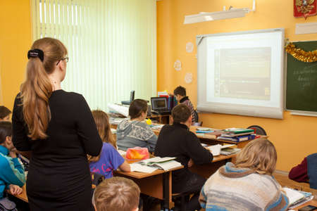Tula, Russia - January 18, 2013: Beautiful young teacher woman standing among sitting students in a middle school class.のeditorial素材