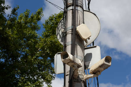 two old cctv security surveillance cameras on street light pole on blue sky backgroundの写真素材