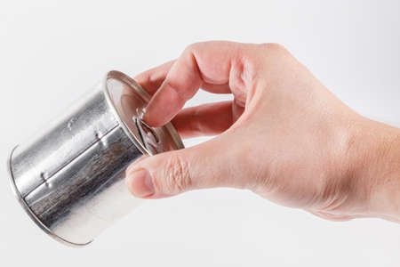 bare caucasian hand opens a tin can with a pull ring on a white backgroundの写真素材