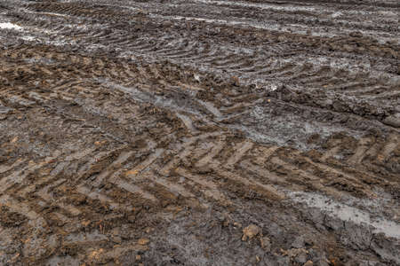 A broken rural country road after the rain. Puddles after rain on a dirt road. Clay, soil and...
