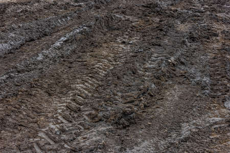 Wet dirt road after rain. Clay, dirt and soil at cloudy day light in autumn season.の写真素材