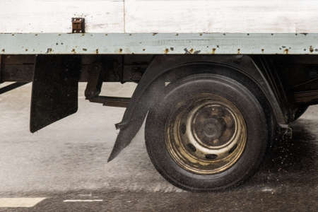 short box truck moving on a wet road with splashes during the day