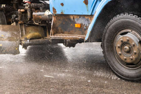 old utility truck moving on asphalt road under rainy day - close-upの写真素材