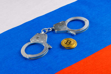roll of russian paper rubles currency and bitcoin shiner chained with handcuffs on russian flag backgroundの写真素材