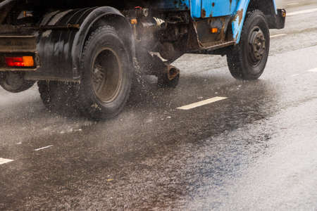 old utility truck moving on asphalt road under rainy day - close-up