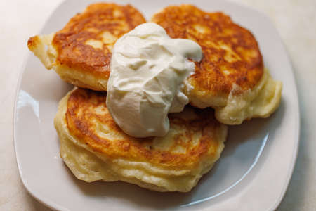 three homemade Russian pancakes on a plate with sour creamの写真素材