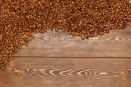 roasted coffee beans laid on brown wooden table surfaceの写真素材