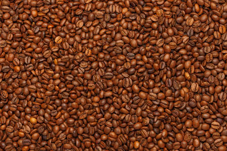 full frame background and texture of roasted coffee beans on flat wooden surface