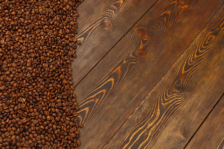 roasted coffee beans laid on brown wooden table surfaceの写真素材