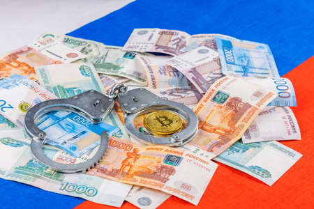 russian paper rubles currency and bitcoin shiner chained with handcuffs on russian flag backgroundの写真素材