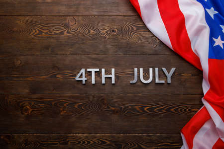 the words 4th july and crumpled usa flag on flat textured wooden surface backgroundの写真素材