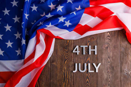 the words 4th july and crumpled usa flag on flat textured wooden surface backgroundの写真素材