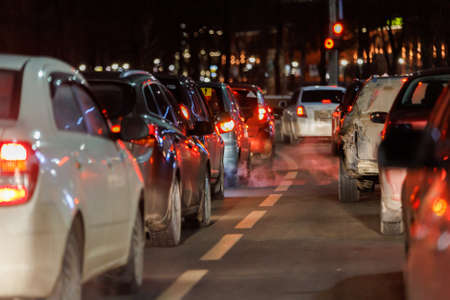 row of cars stopped in front of traffic light at night.