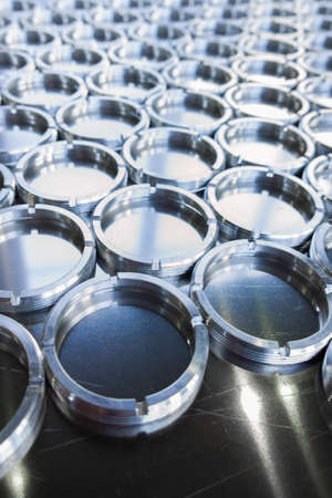 Shiny metal threaded rings after turning and milling. Silver colored rings on flat steel surface...