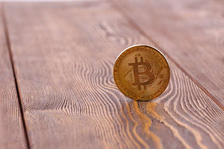 bitcoin coin standing on wooden background - close-up with selective focusの写真素材