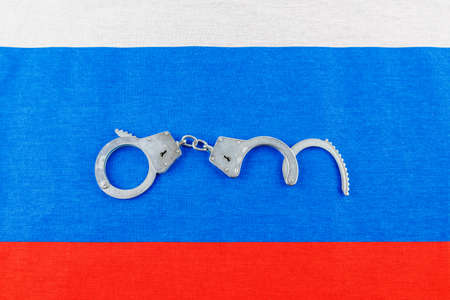 silver metal opened handcuffs laid on Russian flag full-frame backgroundの写真素材
