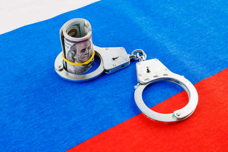 roll of us dollar banknotes in a handcuffs on flat full-frame russian flagの写真素材