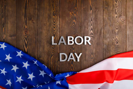 words labor day laid with silver metal letters on wooden surface with crumpled USA flag on bottom side in directly above high angle viewの写真素材
