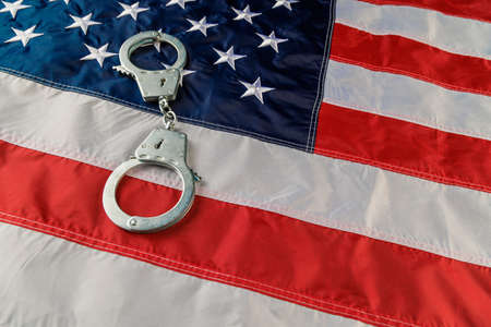 silver metal handcuffs over US flag on flat surfaceの写真素材