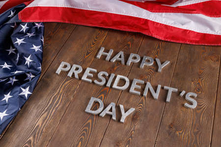 words happy presitdents day laid with real letters on wooden board near US flagの写真素材