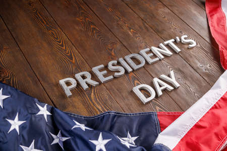 words presitdents day laid with silver letters on wooden surface near US flagの写真素材