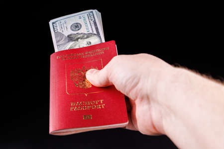 caucasian hand holding russian international passport with inserted US dollarsの写真素材