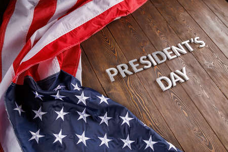 words presitdents day laid with silver letters on wooden surface near US flagの写真素材