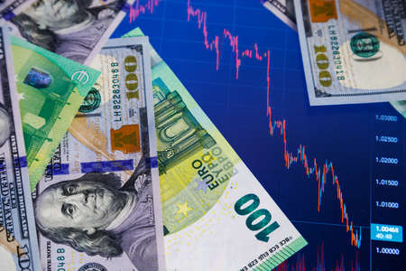 dollar and euro banknotes over digital screen with exchange chart, USD EUR parity concept