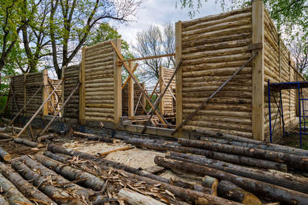 traditional wooden house peeled log wall during cobntruction process with diagonal props
