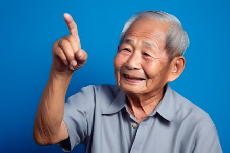 Asian grandfather looking and smiling with rised index finger on blue background, neural network generated artの素材