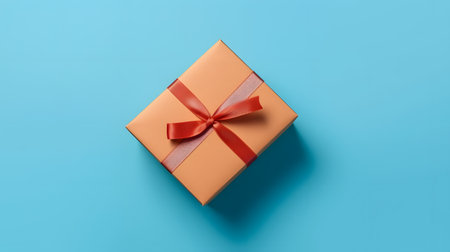 One gift box in craft wrapping paper and red satin ribbon with bow on light blue clean flat surface background, neural network generated imageの素材
