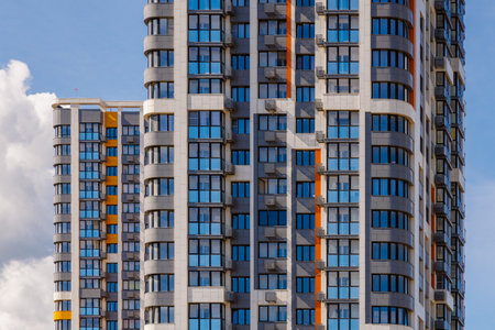 freshly built high rise apartment buildings on blue sky background with white cloudsの写真素材