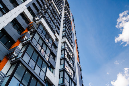 freshly built high rise apartment building on blue sky background with white cloudsの写真素材