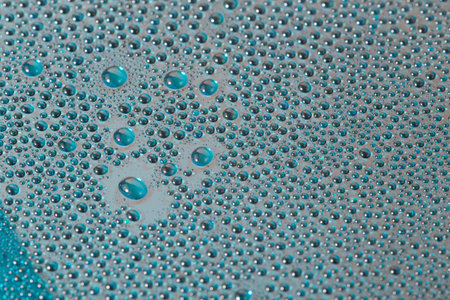 water drops on aurora green pearl glass of modern phone back cover, close-up with selective focus